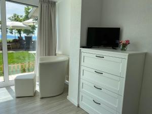eine weiße Kommode mit einem Fernseher darüber in der Unterkunft Hotel Strand-Café mit Gästehaus Charlotte in Langenargen