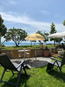 eine Terrasse mit einem Tisch, Stühlen und einem Sonnenschirm in der Unterkunft Hotel Strand-Café mit Gästehaus Charlotte in Langenargen