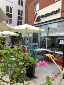 a patio with tables and umbrellas in front of a restaurant at Campanile Saint-Quentin-En-Yvelines in Montigny-le-Bretonneux