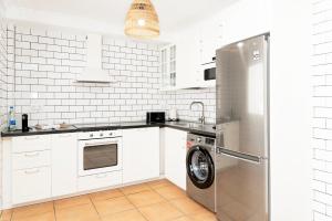 a kitchen with white cabinets and a washer at Villa Veaco Beach with jacuzzi and private pool in Corralejo