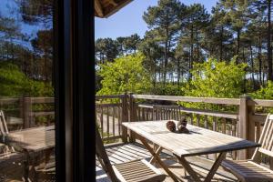 a wooden table on a deck with a cat sitting on it at Domaine du Ferret Restaurant & Spa in Cap-Ferret