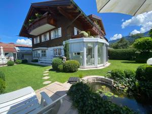 ein Haus mit einem Gewächshaus im Hof in der Unterkunft Ferienwohnung Häusler in Fischen im Allgäu