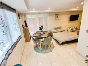 ein Wohnzimmer mit einem Tisch, Stühlen und einem Bett in der Unterkunft Le Petit Rocher 30m2- Studio standing tout confort in Saint-Aignan-Grand-Lieu