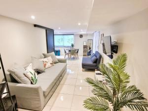 a living room with a couch and a palm tree at Le Petit Rocher 30m2- Studio standing tout confort in Saint-Aignan-Grand-Lieu