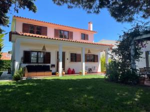 a pink and white house with a green yard at Santa Cruz Beach House in Areias