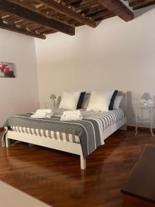 Cama en habitación con paredes blancas y suelo de madera. en Vetus Auximon en Osimo