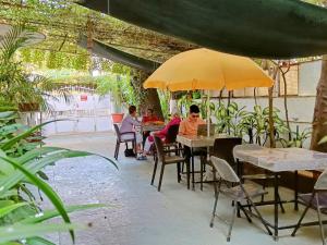 a group of people sitting at tables under an umbrella at Srinekatan Heritage Villa Homestay in Ahmedabad