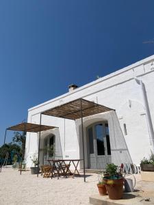 un bâtiment blanc avec des tables et des parasols devant lui dans l'établissement La Piccola Tufaia, à Fasano