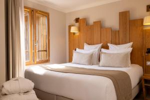 Un dormitorio con una gran cama blanca y una ventana en Domaine du Ferret Restaurant & Spa en Cap-Ferret