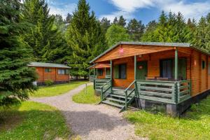 une petite cabane en bois avec une terrasse couverte dans une forêt dans l'établissement Klub Mila Kamień, à Ruciane-Nida