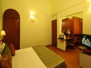 a hotel room with a bed and a television at Lambana Resort in Calangute