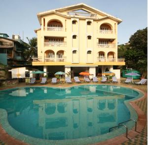a hotel with a swimming pool in front of a building at Lambana Resort in Calangute