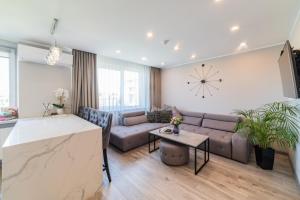 un soggiorno con divano e orologio sul muro di E.D. Luxury Apartaments a Šiauliai