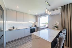 una cocina con armarios blancos y una gran isla blanca en E.D. Luxury Apartaments en Šiauliai