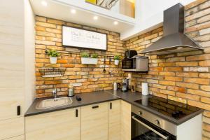 a kitchen with a brick wall and a sink at Pastel paradise with a ray of sunshine in Budapest
