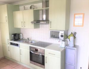 a kitchen with white cabinets and a sink and a microwave at Strandtraum in Glowe +6 photos