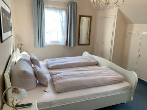 a white bed with pillows on it in a room at Hotel Strand-Café mit Gästehaus Charlotte in Langenargen +29 photos