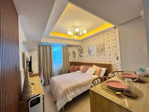 Chic Hideaway at Azure North Bali Tower في سان فيرناندو: غرفة نوم بسرير وطاولة مع كراسي