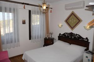 a bedroom with a white bed and a window at Uzum Hotel in Bozcaada