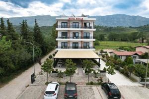 un edificio con auto parcheggiate in un parcheggio di Hotel Roalb a Vlorë