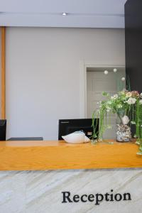 a wooden counter with a vase of flowers on it at Hotel Roalb in Vlorë