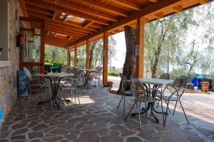 eine Terrasse mit Tischen und Stühlen auf einem Steinboden in der Unterkunft Agricampeggio Paradiso in Brenzone sul Garda
