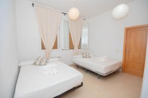 Dos camas en una habitación con dos ventanas. en For You Rentals Hermoso apartamento TEMPORAL Plaza Zerolo - Chueca - Madrid INF1F, en Madrid