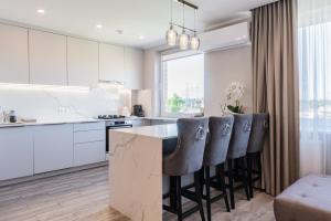 a kitchen with white cabinets and a island with bar stools at E.D. Luxury Apartaments in Šiauliai
