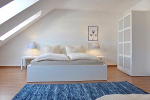ein weißes Schlafzimmer mit einem weißen Bett und 2 Tischen in der Unterkunft Ferienwohnung Orchidee in Lübbenau