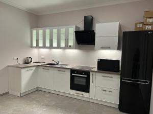 uma cozinha com armários brancos e um frigorífico preto em Gîte « Les Basse des Grouets » em Blois