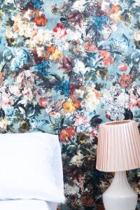 a bedroom with a floral wallpaper with a lamp at Babie Lato in Mrągowo