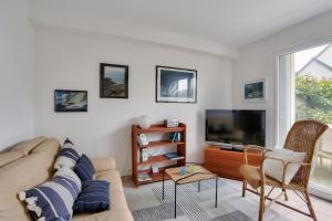 Una sala de estar con un sofá y un televisor de pantalla plana. en Détente et calme sur la Côte d’Émeraude, en Port Blanc