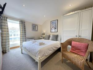 a bedroom with a bed and a chair and a window at Hollies Cottage in St Ives