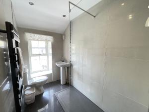 baño con lavabo y aseo y ventana en Hollies Cottage, en St Ives