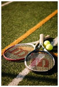 dos raquetas de tenis y pelotas de tenis en una pista en Centrum Eventowo- Konferencyjne Pałacyk Fantazja, 