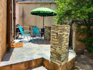 eine Terrasse mit einem Tisch, einem Sonnenschirm und Stühlen in der Unterkunft Maison de 2 chambres avec terrasse amenagee et wifi a Rogliano in Rogliano