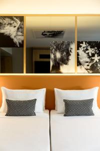 - 2 lits dans une chambre avec des photos sur le mur dans l'établissement Renaissance Paris Vendome Hotel, à Paris