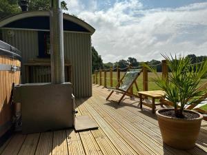 a wooden deck with a stove and a bench at Cleo’s Hut in Cowfold