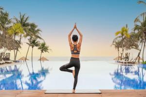 Danang Marriott Resort & Spa في دا نانغ: a woman doing yoga by the pool at a resort