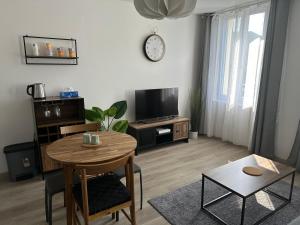 ein Wohnzimmer mit einem Holztisch und einem TV in der Unterkunft Appartement agréable et confortable pour 4 personnes in Le Havre