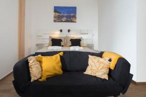 a black couch with yellow pillows in front of a bed at Studio and hot tub in Split