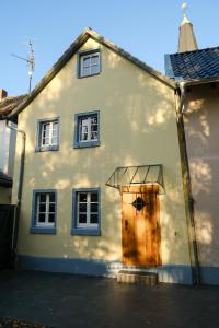 uma casa branca com uma porta de madeira e janelas em Ferienhaus Das Dömchen em Esch