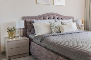 sypialnia z szarym łóżkiem z poduszkami i szafką nocną w obiekcie E.D. Luxury Apartaments w Szawlach