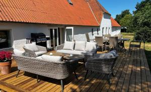 eine Holzterrasse mit Stühlen, Tischen und einem Grill in der Unterkunft Større luksus Hus ved Assens in Assens
