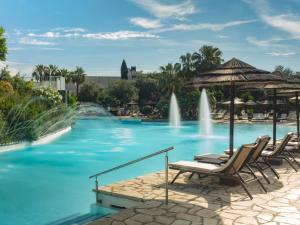 a swimming pool with chairs and a fountain at Dreams Corfu Resort & Spa - All Inclusive in Gouvia