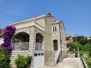 una casa de piedra con escaleras y flores púrpuras en Guest House Franica & Pero Lobrovic, en Slano