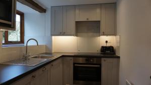 a kitchen with white cabinets and a sink and a stove at Barley Cottage - 5* Cyfie Farm with log burner and private covered hot tub in Llanfyllin