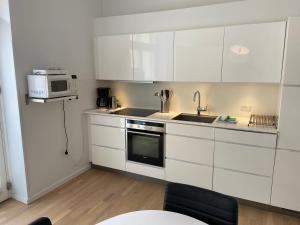 a kitchen with white cabinets and a sink and a microwave at City Center Apartments 694 in Copenhagen