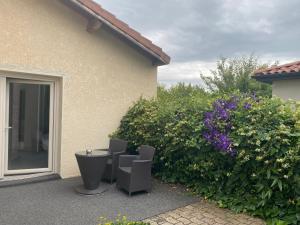 a patio with chairs and flowers next to a house at Contact Hôtels Les Pierres Dorées in Ambérieux d'Azergues