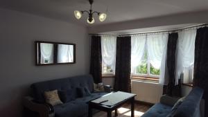 a living room with a blue couch and a window at APARTHOTEL "Apartamenty KORONA" w Cieplicach przy basenach Termy Cieplickie koronacieplic,pl in Jelenia Góra
